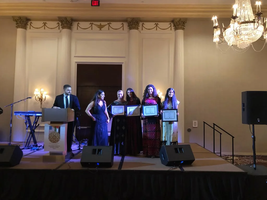 Award recipients holding framed certificates onstage at a community ceremony
