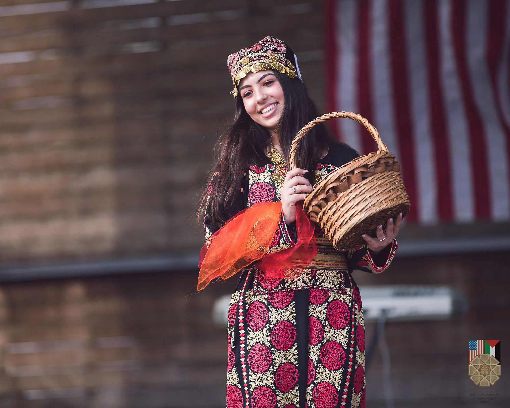 A young woman in traditional Palestinian dress holding a woven basket at the 2019 Houston Palestinian Festival