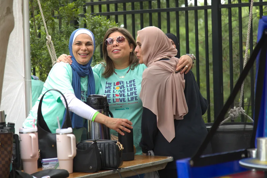 Three women in PACC event shirts greeting one another at the 2025 festival