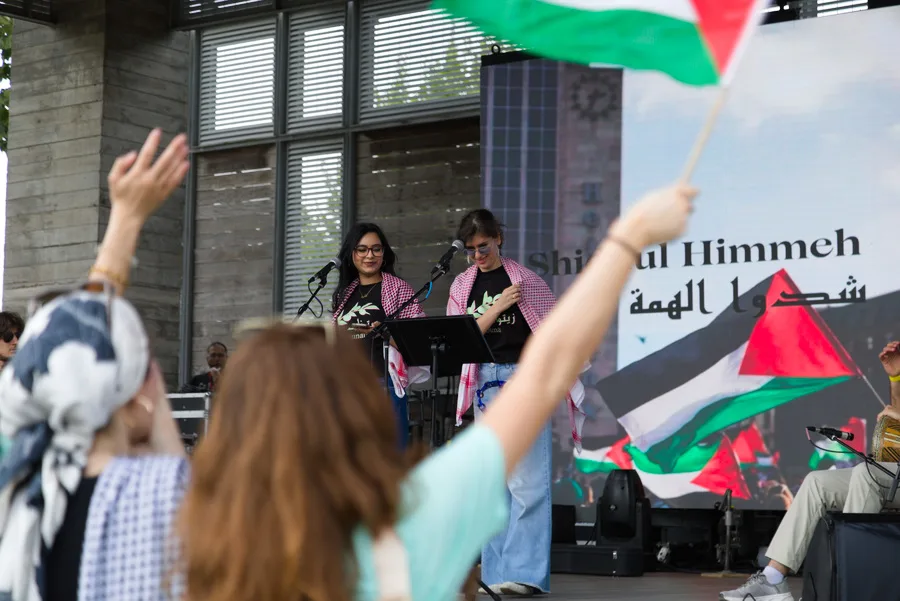 Festival visitors raising Palestinian flags while two speakers stand onstage