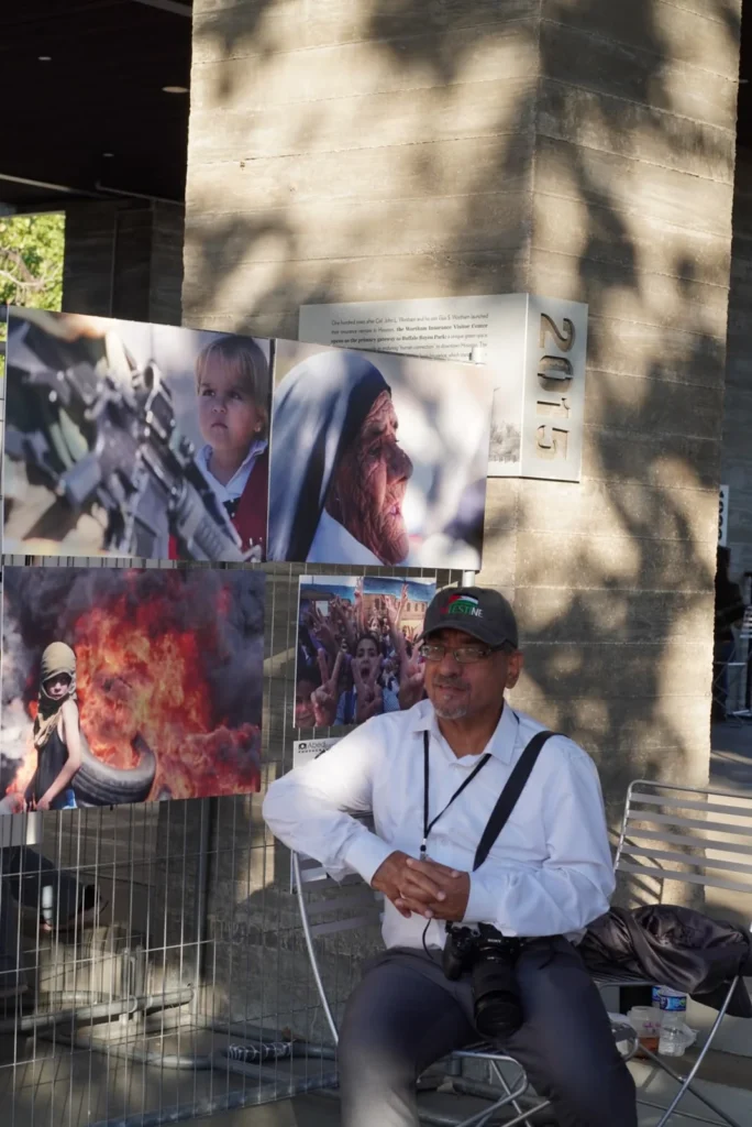 Palestinian photojournalist Abed Qusini beside a photography display at the Houston Palestinian Festival.
