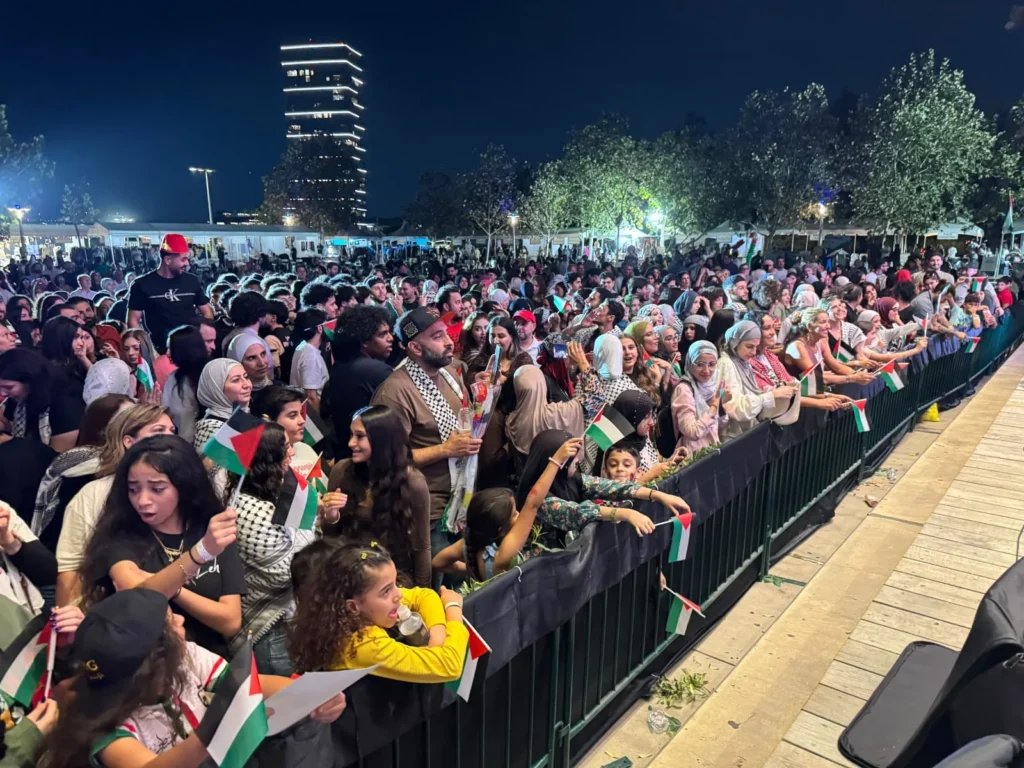 Festival audience members waving Palestinian flags during the night performance.