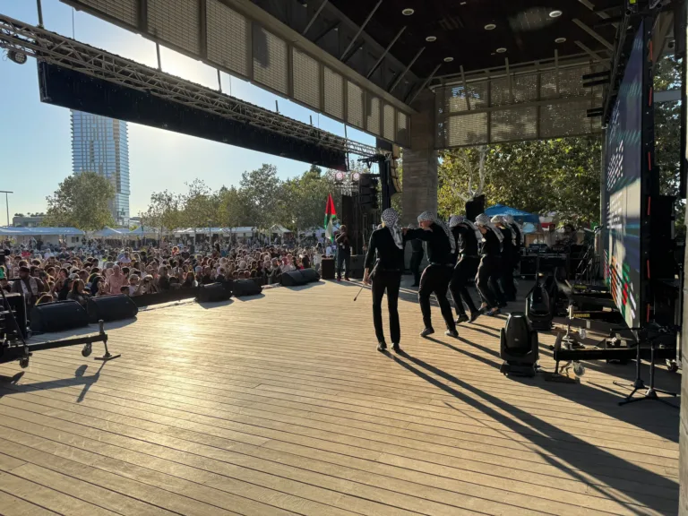 A line of dabke dancers performing onstage in front of the festival audience.