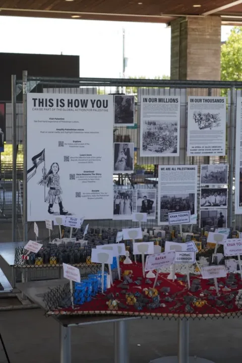 An educational display with informational panels and a miniature model at the festival.