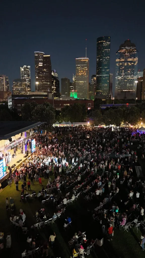 An overhead view of the festival crowd and stage beneath the illuminated Houston skyline.