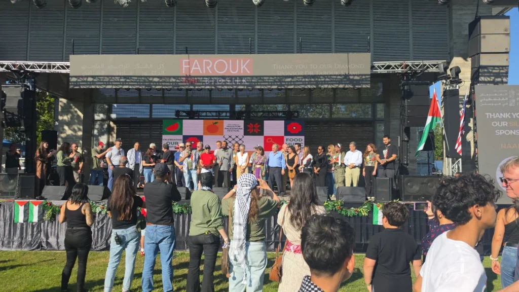 Rep. Al Green speaking onstage at the Houston Palestinian Festival, with participants and audience members.