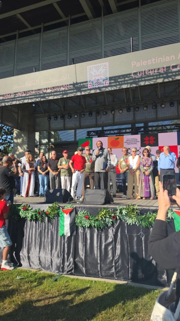 Rep. Al Green speaking onstage at the Houston Palestinian Festival, with the audience in the foreground.